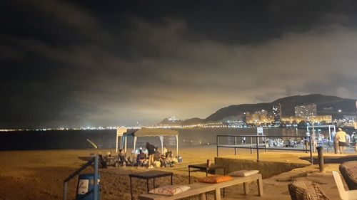 Illuminated beach against sky at night