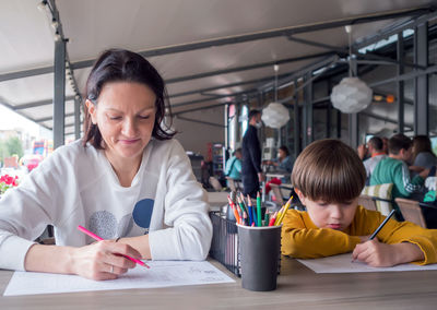 Mom and son is playing sea battle at street cafe. family games. strategy type guessing game .