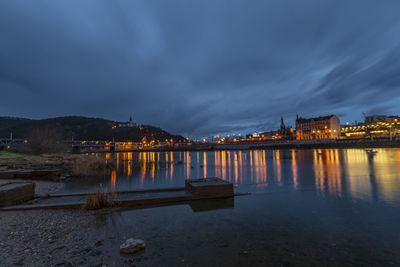 Illuminated bridge over river against sky at night