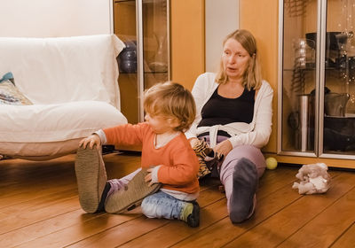 Happy friends sitting on wooden floor at home