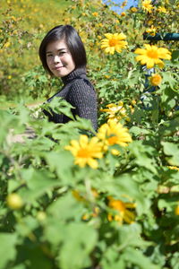 Portrait of woman standing amidst yellow flowering plants
