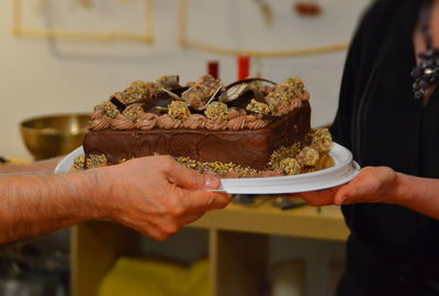 Cropped hands of people holding cake plate