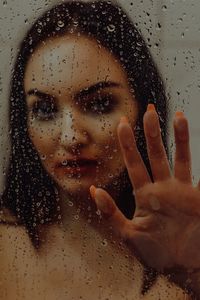 Close-up portrait of woman in wet glass