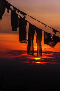 Prayer flag hanging on clothesline against an orange sky