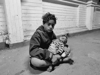 Portrait of boy with baby girl sitting on road