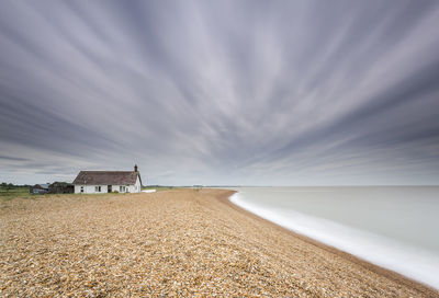 House at scenic beach against sky