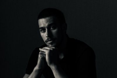 Portrait of young man with hand on chin against black background