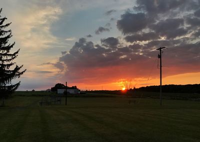 Scenic view of silhouette field against sky at sunset