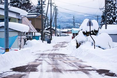 Snow covered street amidst houses and buildings during winter