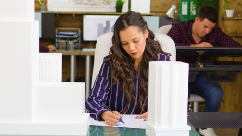 Portrait of young woman using mobile phone while sitting on table