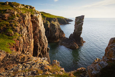 Rock formations by sea against sky