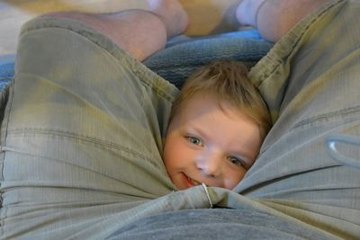 Portrait of cute boy by father legs at home