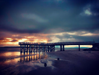 Pier over sea against sky during sunset