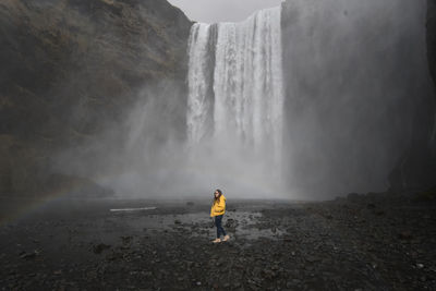 Rear view of man standing against waterfall