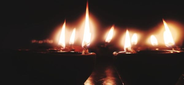 Close-up of lit candles burning in dark