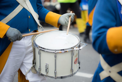 Midsection of man playing drum on street during carnival