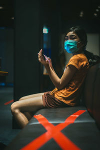 Girl wearing mask looking away while using phone
