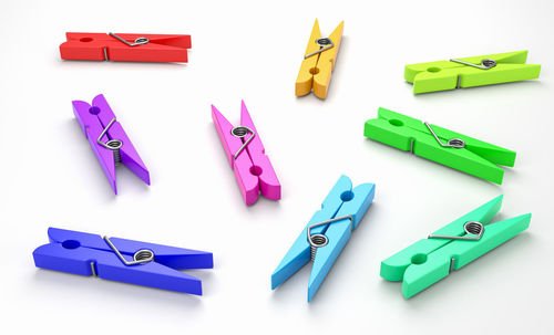 High angle view of multi colored clothespins on white background