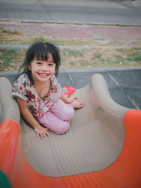 Portrait of cute smiling girl sliding in playground