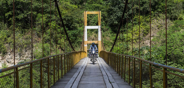 Man driving touring motorbike on suspension bridge in peru