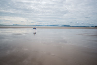 Man walking on beach against sky