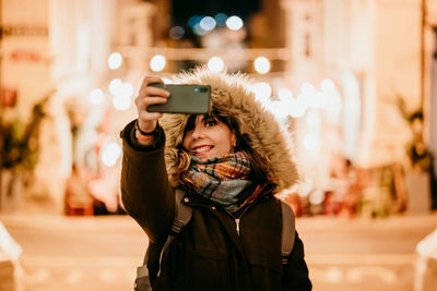 Portrait of smiling young woman using smart phone in winter