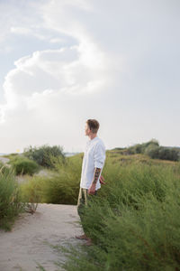 Side view of woman standing on field against sky