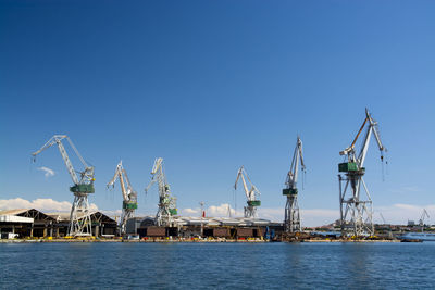 Cranes at commercial dock against clear sky