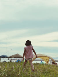 Rear view of young woman standing against sky during sunset