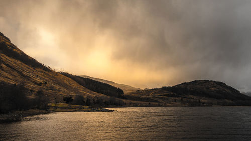 Scenic view of lake by mountains against sky