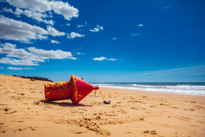 Red umbrella on beach against blue sky