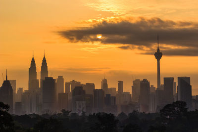 Modern buildings in city against sky during sunset