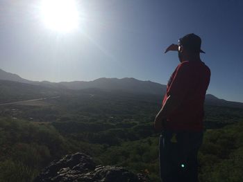 Rear view of man standing on mountain against sky