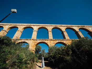 Low angle view of arch bridge against clear blue sky