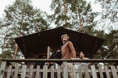 Low angle view of smiling friends standing at porch against house