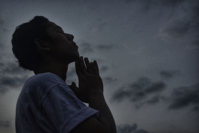 Man praying against sky