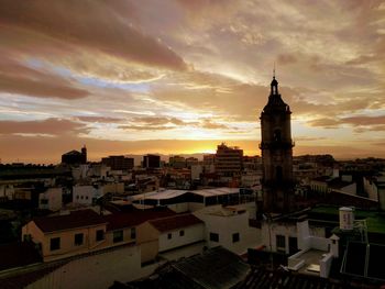 High angle view of buildings in town against cloudy sky