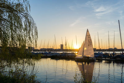 Sailboats moored in lake against sky during sunset