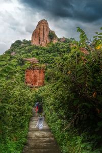 Rear view of woman walking on mountain against sky