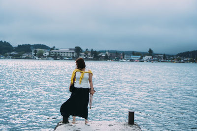 Rear view of woman standing in city against sky