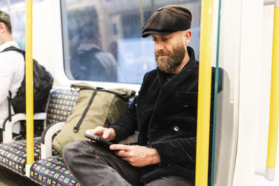 Man using smart phone sitting in train