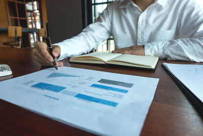 Midsection of man reading book on table