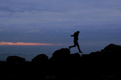 Silhouette of person standing on landscape at sunset