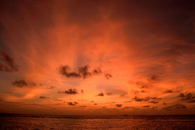 Scenic view of sea against dramatic sky during sunset