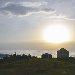 Houses on field against sky during sunset