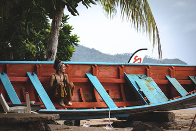 View of girl smiling in an abandoned boat against trees