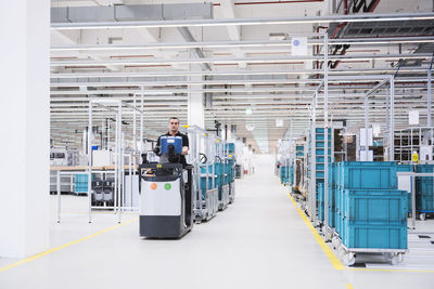 Man driving a tugger train in factory shop floor