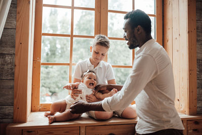 Father and son sitting on window