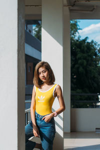 Portrait of a young woman standing against wall