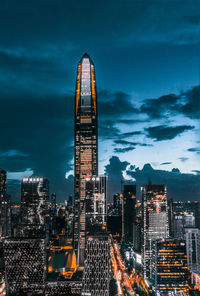 Illuminated modern buildings in city against sky at night